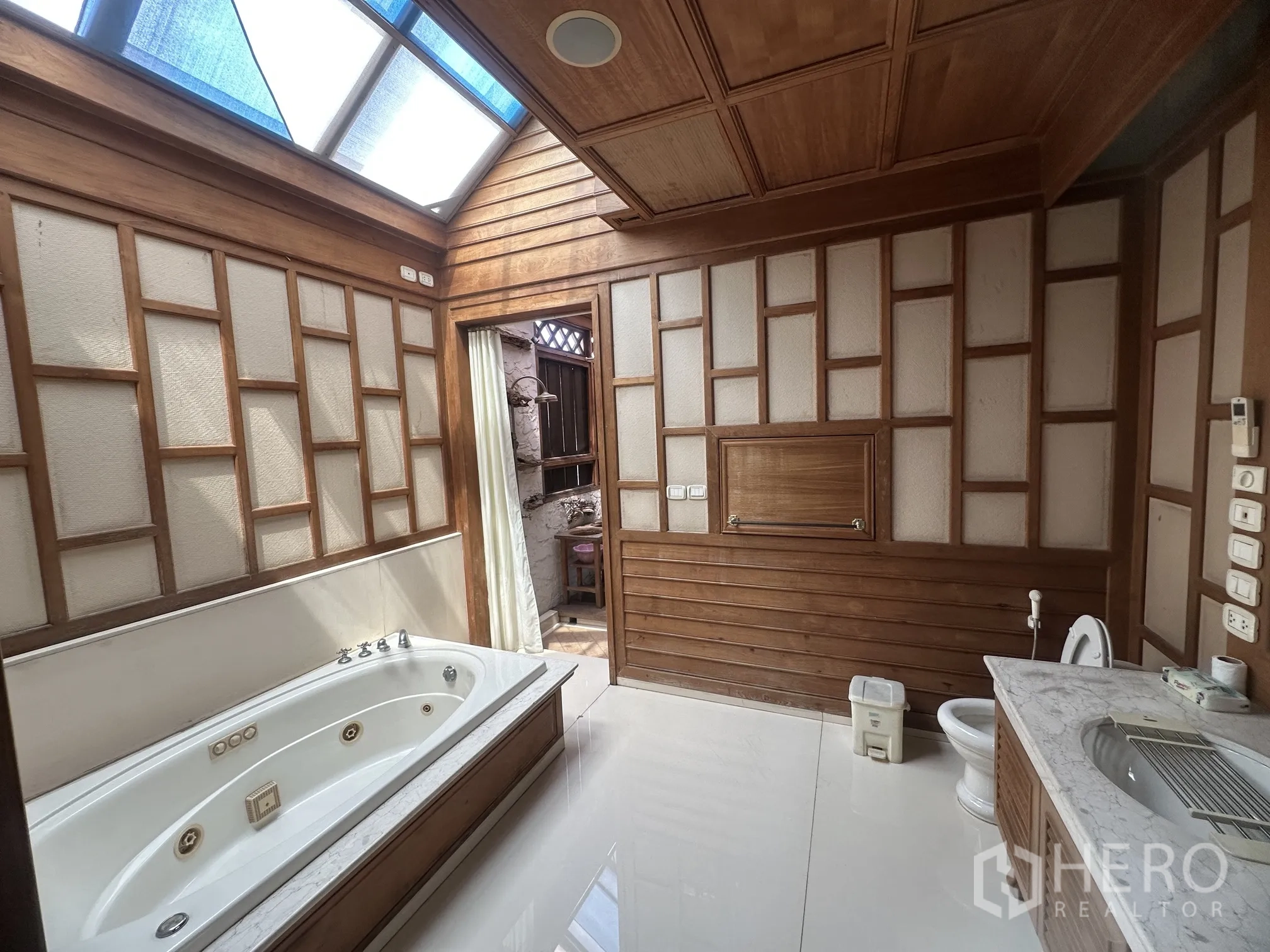 Detached House for rent in Lam Luk Ka, Pathum Thani - Large bathroom with skylight, built-in bathtub, and wood-panel details.