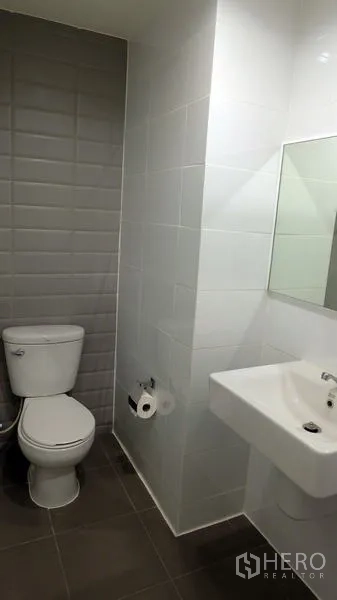 公寓 出售在Khlong Toei, Bangkok - 整洁浴室，设有白色洗手盆、马桶与灰色纹理墙砖。