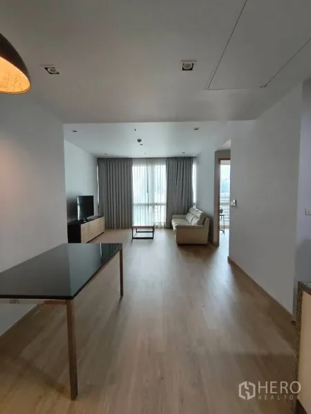 公寓 出租在Khlong Toei, Bangkok - 开放式客餐厅，浅色木地板，沙发、电视柜与落地窗城市景观。