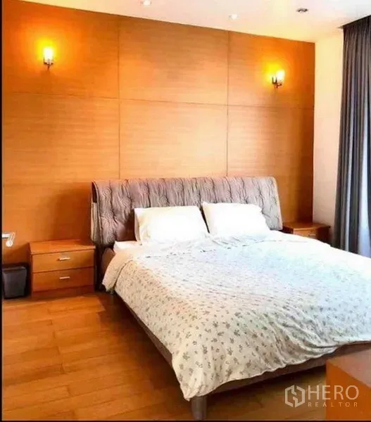 คอนโด ให้เช่าหรือขายในRatchathewi, Bangkok - ห้องนอนอบอุ่นพร้อมเตียงขนาดใหญ่ ผนังลายไม้ และโต๊ะข้างเตียง