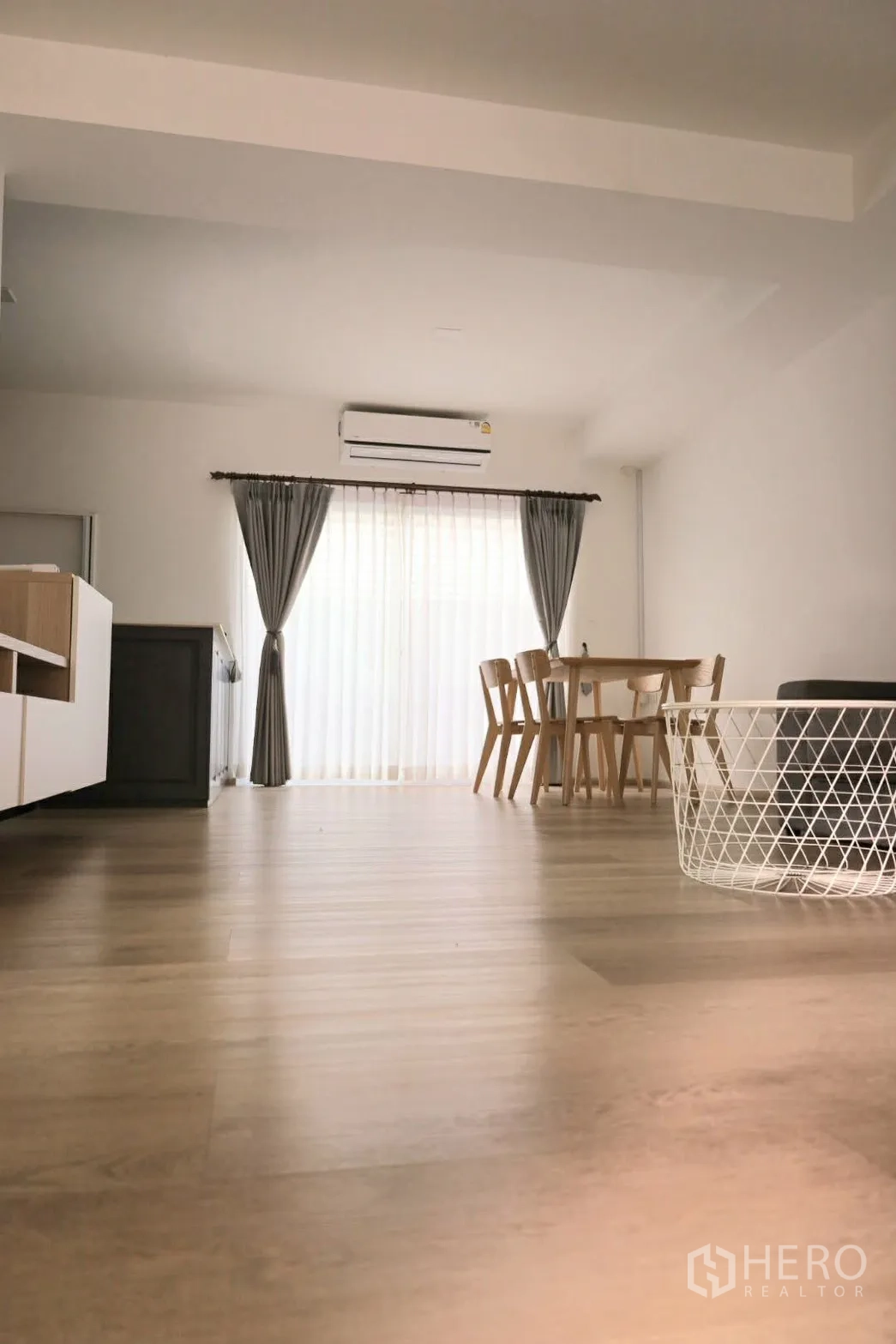 联排别墅 for rent in Prawet, Bangkok - 开放式客餐厅，配空调、窗帘与木质餐桌椅。