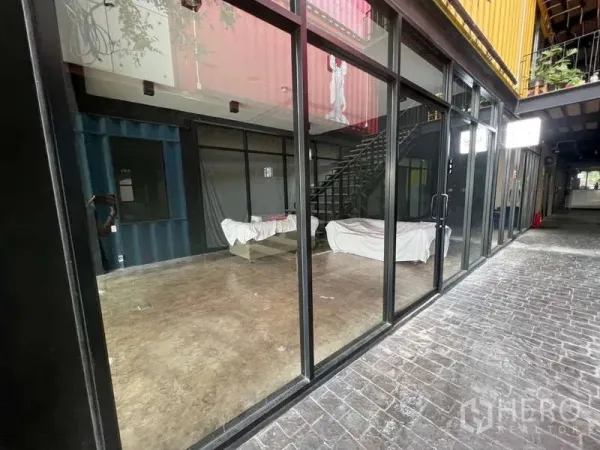 พื้นที่ขายปลีก ให้เช่า - หน้าร้านติดคอร์ทยาร์ด กระจกเต็มความสูง ทางเดินปูอิฐและบันไดขึ้นชั้นบน