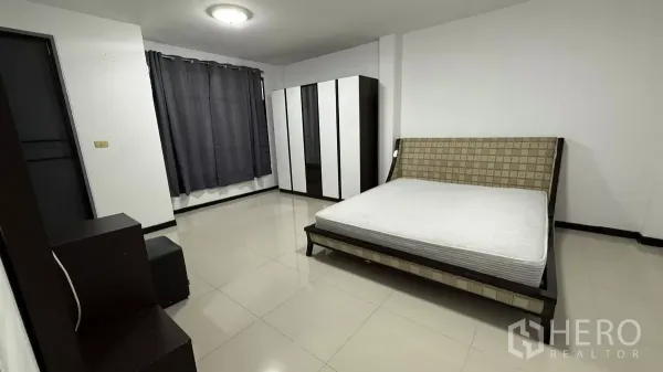 带办公室的家 出租在Bang Na, Bangkok - 宽敞主卧，大片床架、衣柜组合、灰色窗帘和亮面地砖。