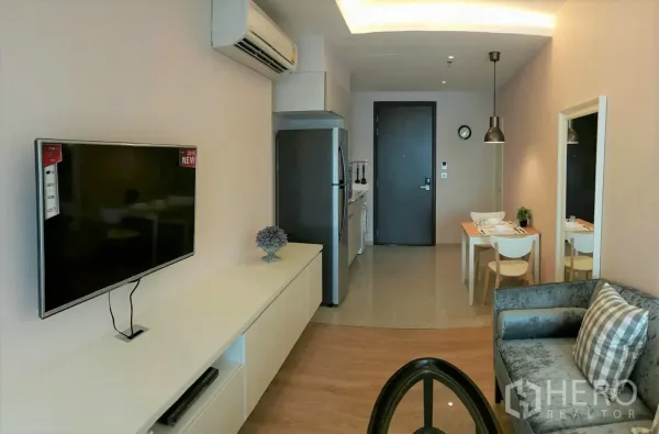 คอนโด ให้เช่าในWatthana, Bangkok - ห้องนั่งเล่นสว่างพร้อมทีวีติดผนัง เครื่องปรับอากาศ โซฟา และมุมทานอาหารข้างครัวขนาดกะทัดรัด