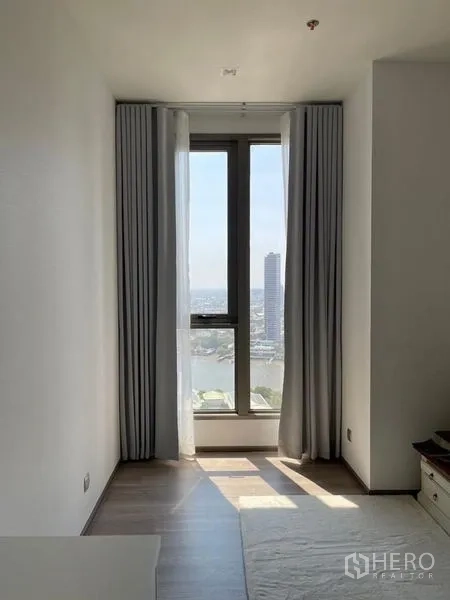 Condominium for rent in Bang Kho Laem, Bangkok - Tall window with curtains opening to a river and skyline view.