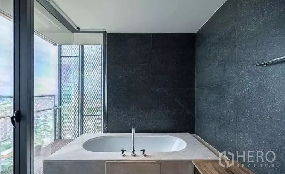 Condominium for rent in Sathon, Bangkok - Bathroom with soaking tub set by the window overlooking the city.