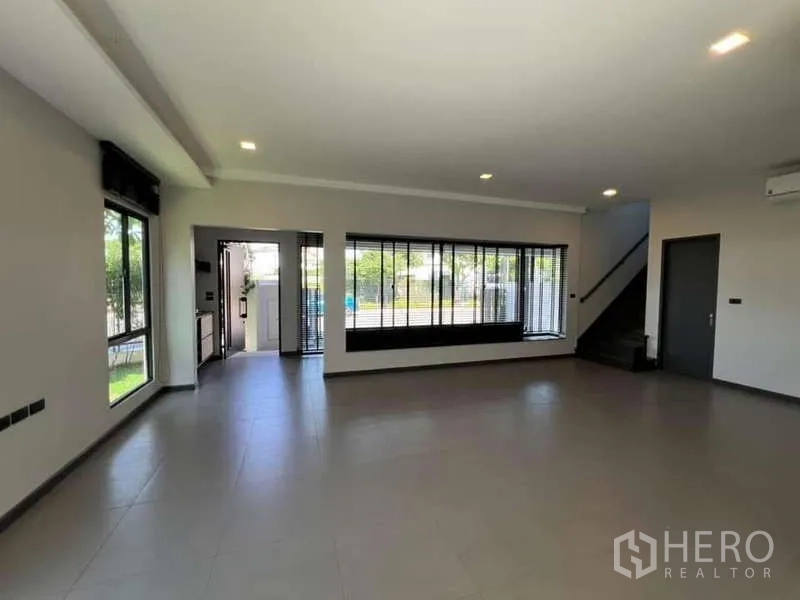 Detached House for rent or sale in Bang Phli, Samut Prakan - Expansive ground‑floor living space with wide windows and a staircase to the upper floor.