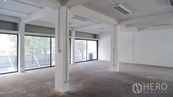 办公空间 出租在Watthana, Bangkok - 开放式办公室，白色立柱与整墙落地窗引入自然光。