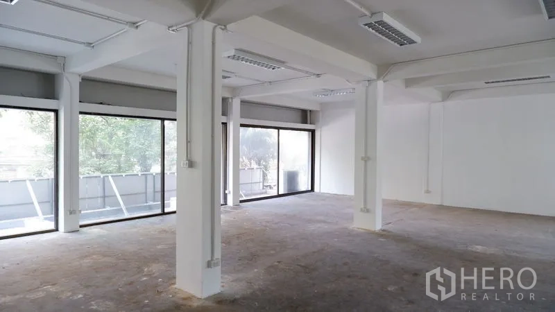 办公空间 出租在Watthana, Bangkok - 开放式办公室，白色立柱与整墙落地窗引入自然光。