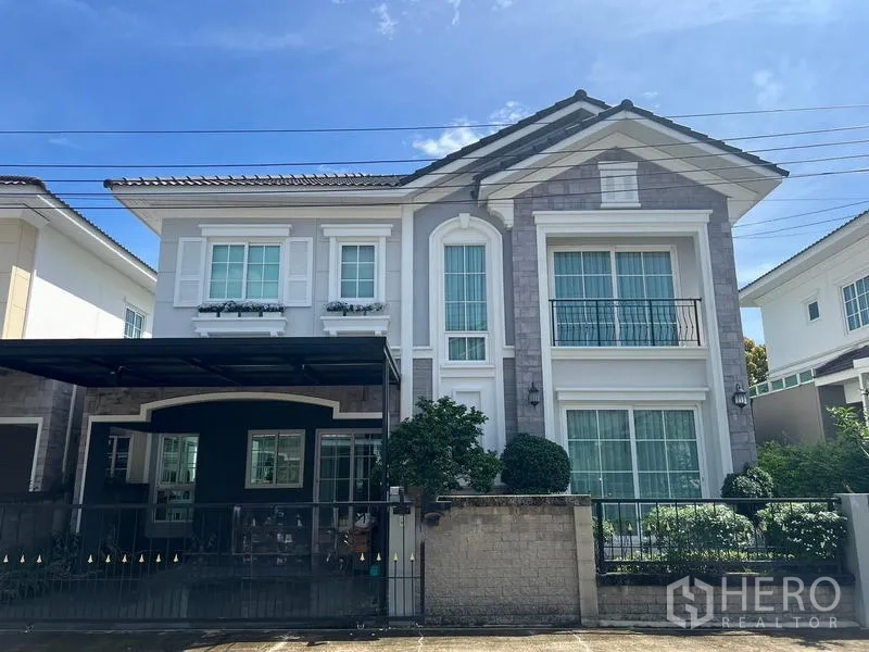 Detached House for rent or sale - Two-storey detached house front facade with gate, balcony and manicured shrubs.