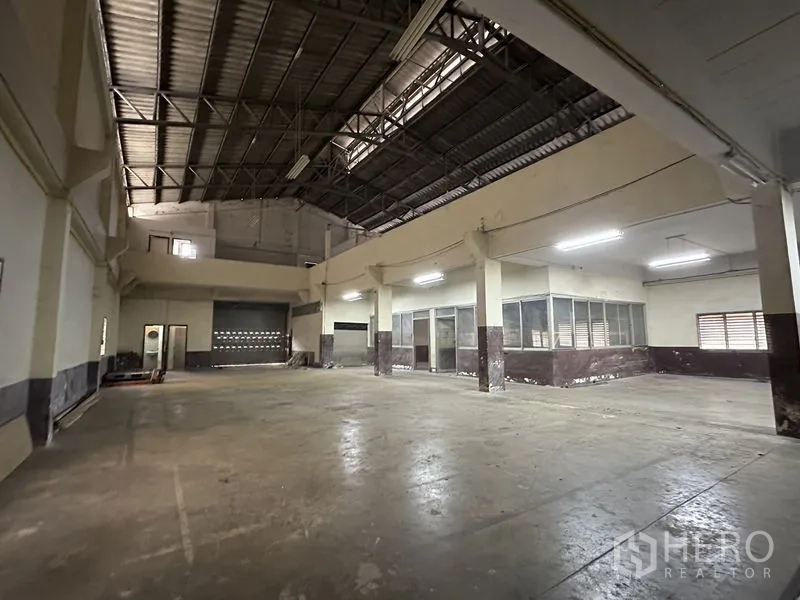 工厂 出租在Bang Bua Thong, Nonthaburi - 高挑钢桁架屋顶的仓库大厅，卷闸门与封闭办公室
