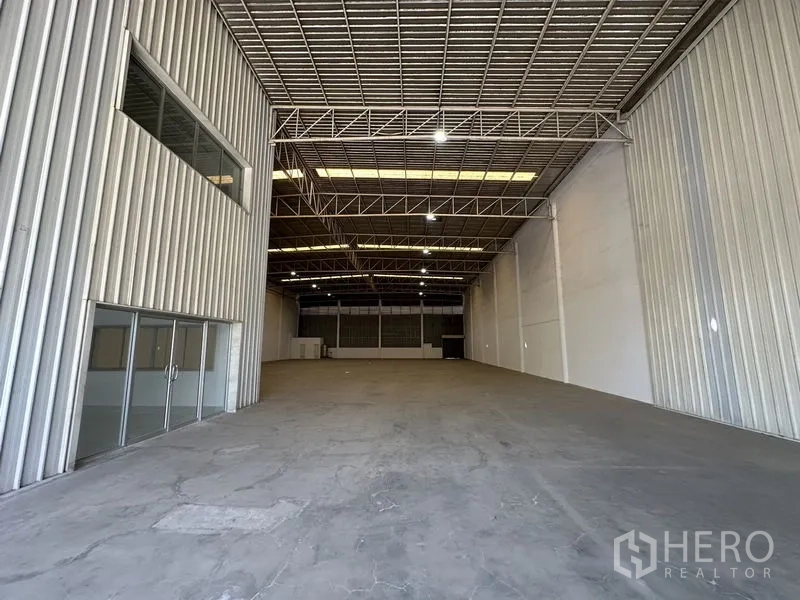 工厂 出租在Khlong Luang, Pathum Thani - 宽敞仓库内部，高钢桁架屋顶、采光板与混凝土地坪。