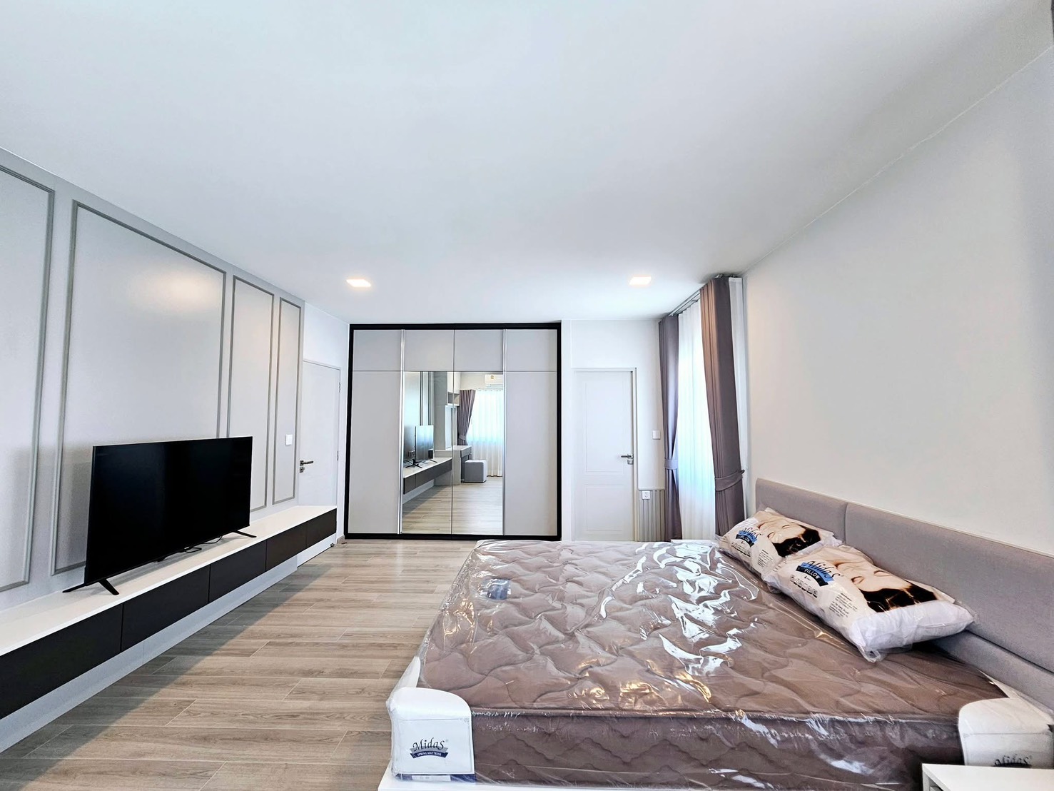 Detached House for rent in Bang Phli, Samut Prakan - Master bedroom featuring mirrored wardrobe, TV console, and wood flooring.