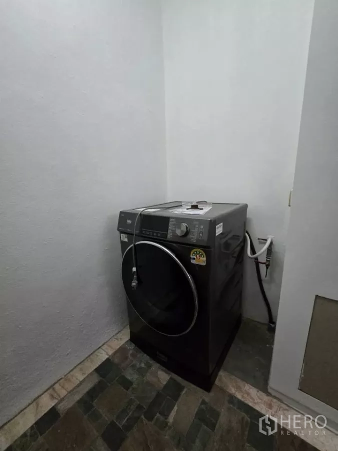 Condominium for rent in Pathum Wan, Bangkok - Laundry nook with front-load washing machine and tiled floor.