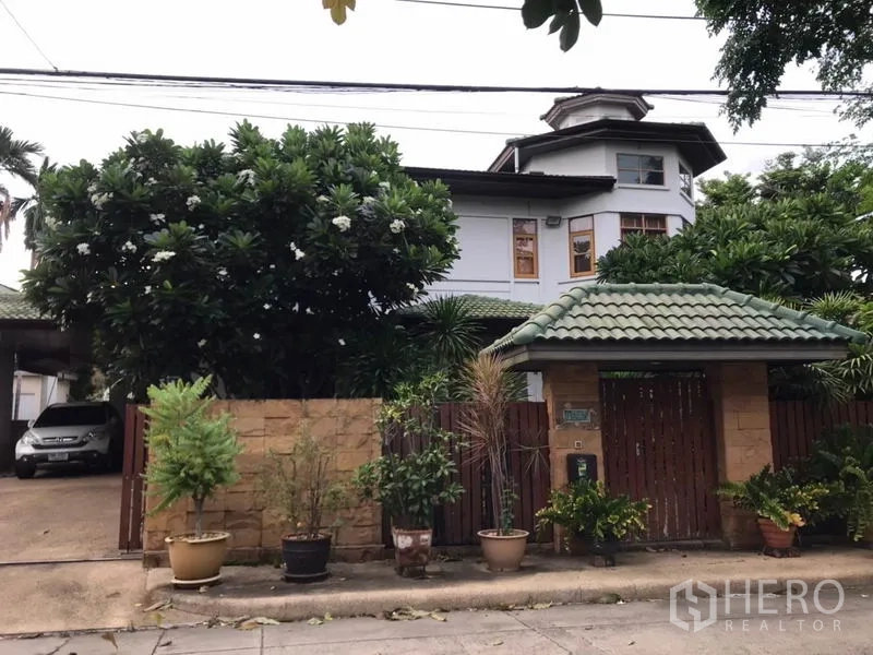 独立式住宅 出售在Lat Phrao, Bangkok - 临街庭院大门与绿瓦门亭，车道及成树掩映。
