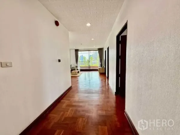 Condominium for rent - Long hallway leading to a bright lounge with wooden floors and recessed lighting.