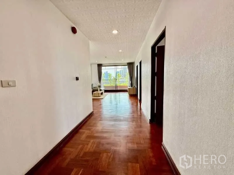 Condominium for rent - Long hallway leading to a bright lounge with wooden floors and recessed lighting.