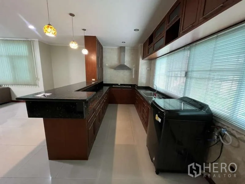 สำนักงานที่บ้าน ให้เช่าหรือขายในMin Buri, Bangkok - ครัวรูปตัว U เคาน์เตอร์หินสีดำ เครื่องดูดควัน และหน้าต่างบานยาวรับแสง