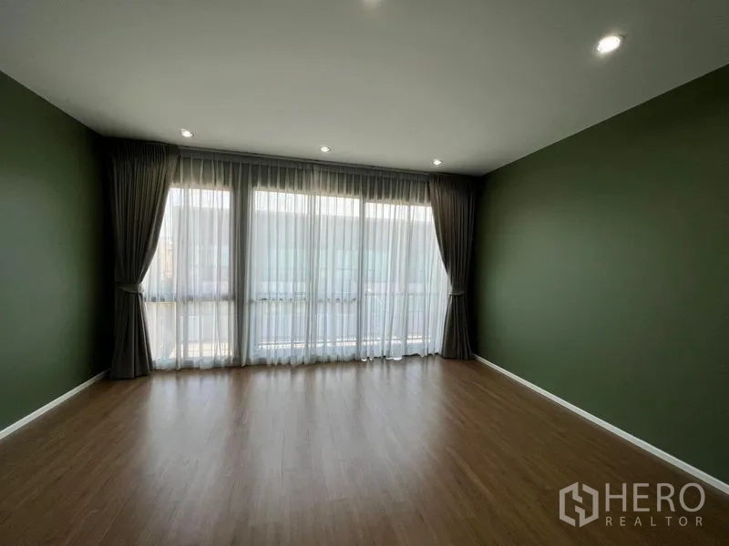 ทาวน์เฮาส์ ให้เช่าในSaphan Sung, Bangkok - ห้องโล่งกว้าง ผนังสีเขียว พื้นไม้ และหน้าต่างกว้างพร้อมผ้าม่าน