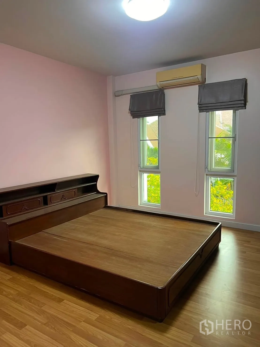 Detached House for rent in Watthana, Bangkok - Bedroom with wooden platform bed, pink wall, twin windows, and air conditioner.