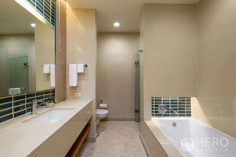 Condominium for rent in Bang Kho Laem, Bangkok - Modern bathroom with long vanity, bathtub, separate glass shower and neutral tiles.