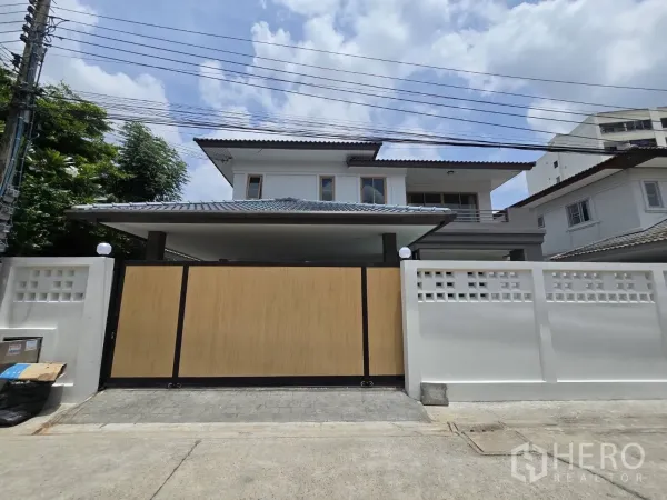 บ้าน ขายในSuan Luang, Bangkok - มุมมองหน้าบ้านพร้อมรั้วปูนสีขาวและประตูสไลด์ลายไม้ขนาดกว้าง