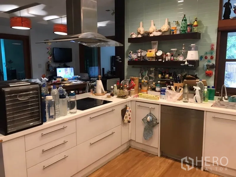 独立式住宅 出售在Lat Phrao, Bangkok - 现代U型厨房，白色橱柜、台灶与岛式烟机，开放层架与木地板。