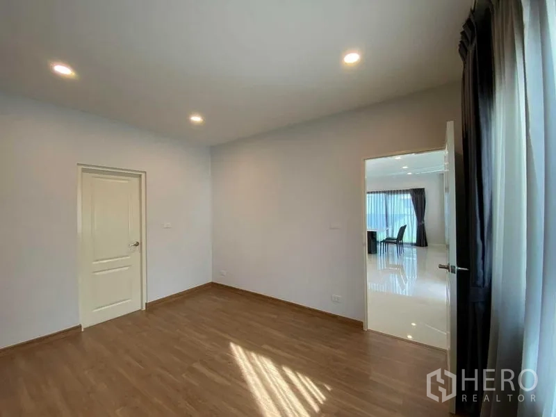 Detached House for rent in Don Mueang, Bangkok - Ground-floor room with wood floors and access to the living area.