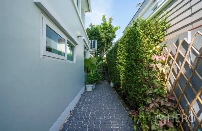 Detached House for rent in Prawet, Bangkok - Paved side path beside the house lined with tall privacy hedges and trellis.