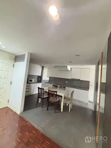 Condominium for rent - Open kitchen with white cabinets, stone backsplash and a dining table for four.