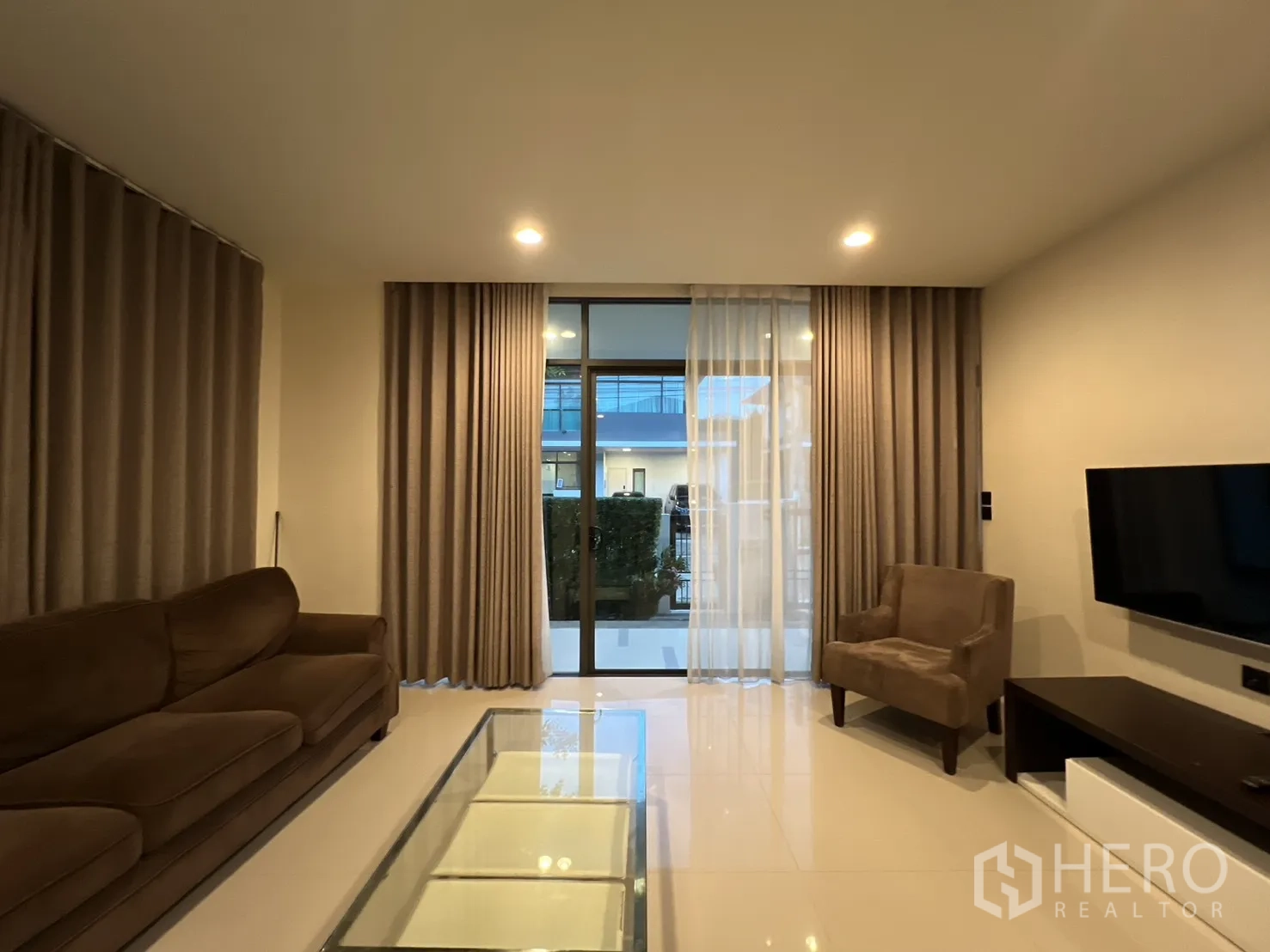 บ้าน ให้เช่าหรือขายในBang Kapi, Bangkok - ห้องนั่งเล่นมีประตูกระจกเต็มบานและผนังติดทีวี