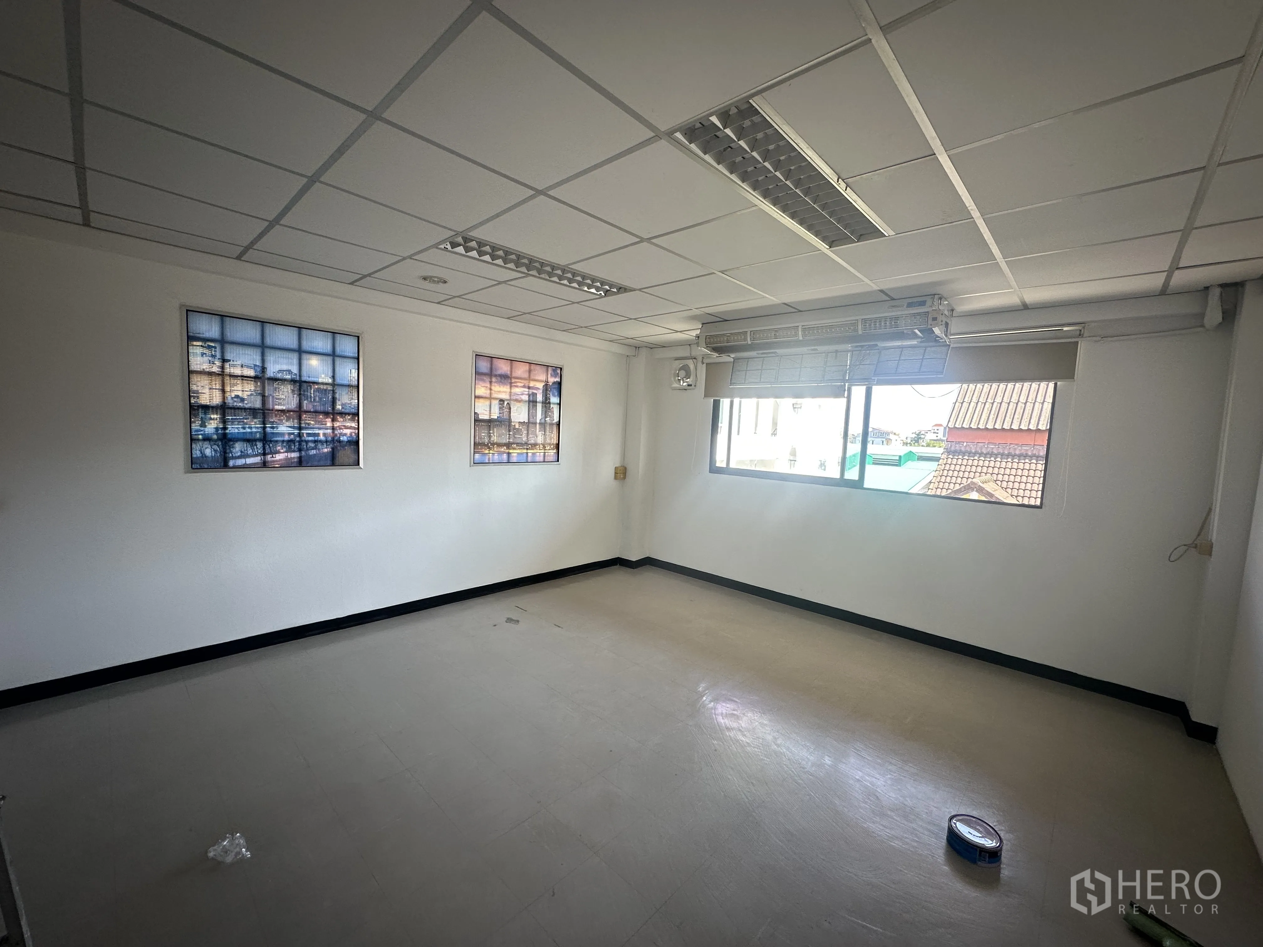 Office Space for rent in Watthana, Bangkok - Bright office room with a large window, framed wall art, drop ceiling lights and a roller blind.