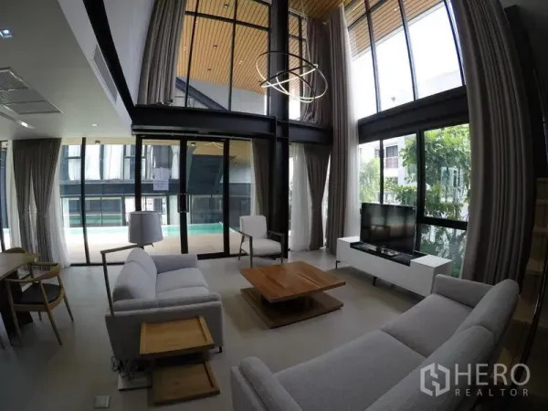 อพาร์ทเมนท์ ให้เช่าในKhlong Toei, Bangkok - ห้องนั่งเล่นเพดานสูง กระจกบานใหญ่ โซฟาสีเทา มองเห็นระเบียงสระว่ายน้ำ