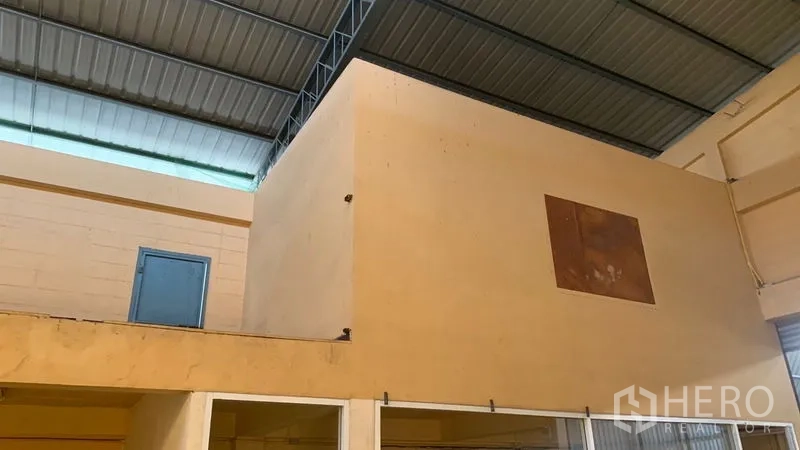 Warehouse for rent in Mueang Nakhon Pathom, Nakhon Pathom - Mezzanine-style internal room block with a blue metal door beneath the steel roof.