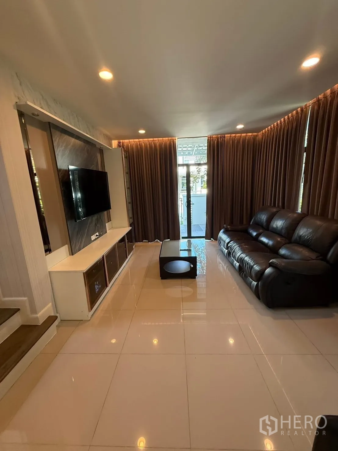 Detached House for rent in Prawet, Bangkok - Spacious living area with leather sofa, coffee table and floor-to-ceiling curtains.