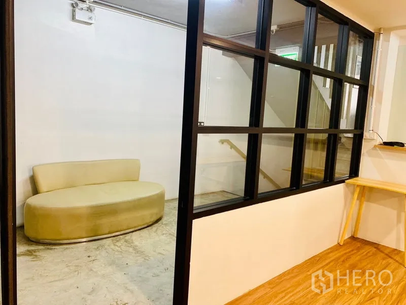 办公空间 出租在Bang Rak, Bangkok - 接待休息区，玻璃隔墙与弧形沙发，临楼梯