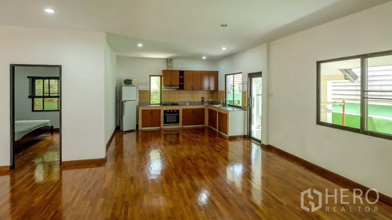 Detached House for sale in Bang Lamung, Chon Buri - Open-plan living area with European kitchen, teakwood floors, and windows bringing natural light.