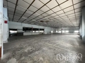 Factory for rent in Phra Pradaeng, Samut Prakan - Large indoor storage area with concrete floor and partitioned sections under panel ceiling.