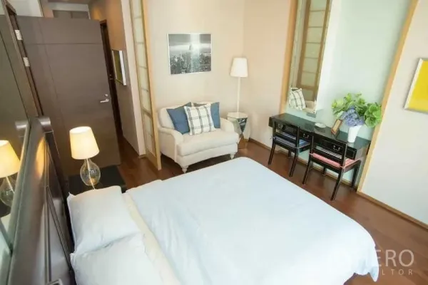 Condominium for rent in Watthana, Bangkok - Bedroom corner with loveseat, desk and lamps, warm wood floors and neutral decor.