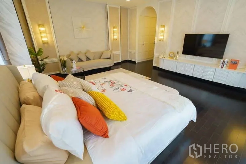 Detached House for rent or sale in Bang Phli, Samut Prakan - Spacious master bedroom with TV wall, sofa corner and dark wood flooring.