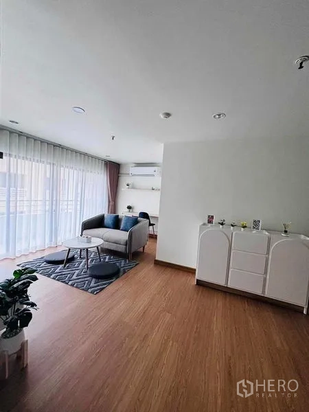 店屋 出租在Watthana, Bangkok - 宽敞客厅，木地板与柜体，通向明亮阳台。