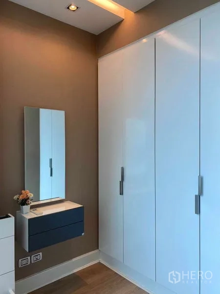 คอนโด ให้เช่าในBangkok - ตู้เสื้อผ้าบิวท์อินสีขาวบานใหญ่และกระจกพร้อมตู้ลอยในห้องนอน