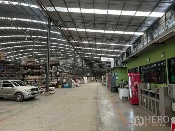 Factory for rent in Pathum Thani - Main aisle inside the factory with a green office block and vending machines along the walkway.