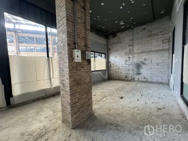 พื้นที่ขายปลีก ให้เช่าในKhlong Toei, Bangkok - มุมห้องค้าปลีกมีเสาอิฐและช่องแสงหลายด้าน พื้นคอนกรีตพร้อมตกแต่ง