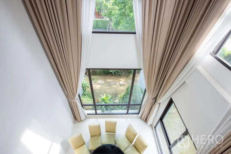 独立式住宅 出租或出售在Kanchanaburi - 挑高客厅，落地窗面向花园景观。