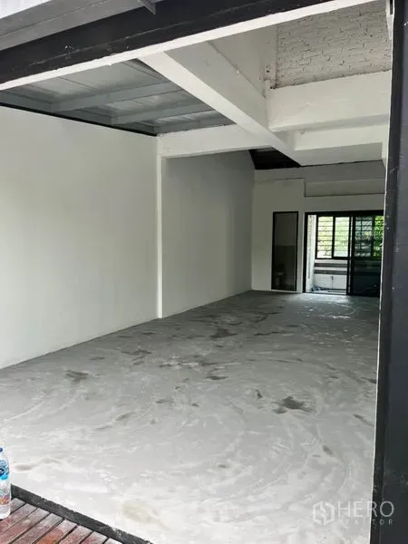 พื้นที่ขายปลีก ให้เช่าในWatthana, Bangkok - พื้นที่ร้านค้าเปิดโล่ง มุมมองจากทางเข้า เห็นโครงคานเปลือยและประตูกระจกบานเลื่อนไปยังระเบียงร่มรื่น