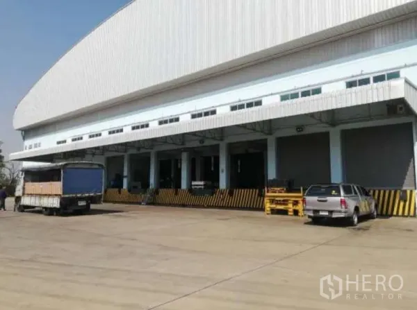 คลังสินค้า ให้เช่าในNong Chok, Bangkok - แถวช่องโหลดสินค้าพร้อมประตูม้วนและลานคอนกรีตกว้าง มีรถจอดรอโหลด