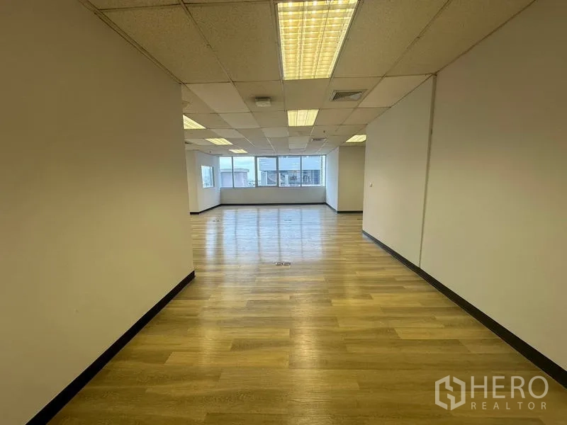 办公空间 出租在Phra Khanong, Bangkok - 走廊视角的开放办公室，木地板、网格天花与采光窗户。