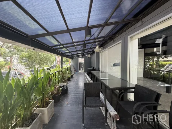 店屋 出租在Wang Thonglang, Bangkok - 带顶棚的阳台露台，摆放玻璃桌与绿植，适合咖啡座位。