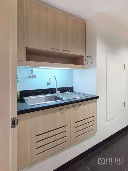 Condominium for rent in Yan Nawa, Bangkok - Compact pantry with double sink, light wood cabinets and black countertop.